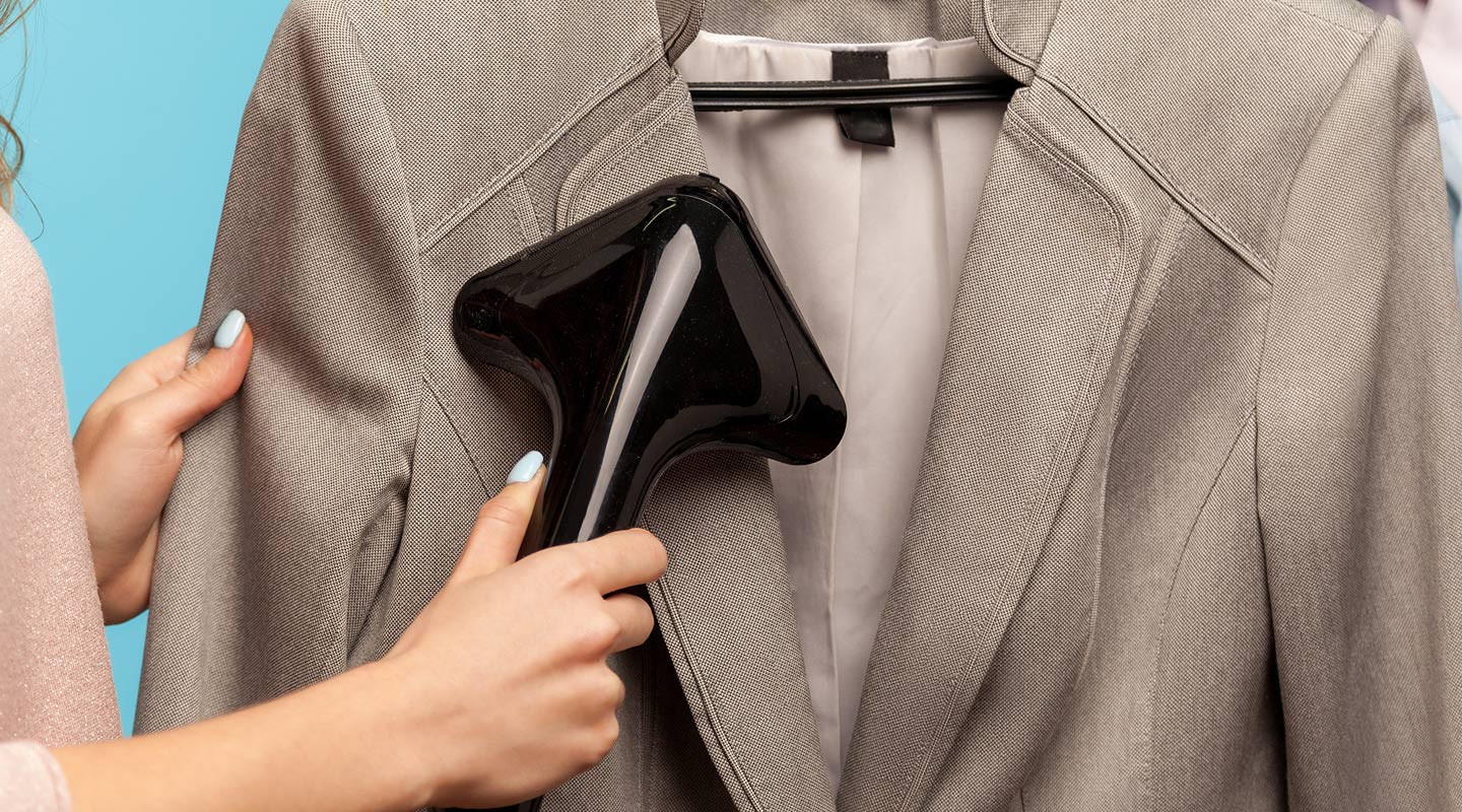 Person using a garment steamer on a suit jacket