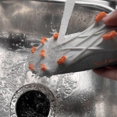 Rinsing the bottom of cleats under a faucet