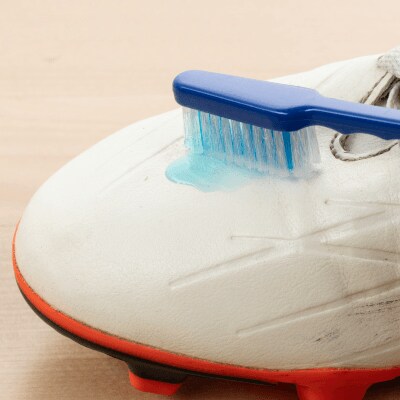 Toothbrush scrubbing a white cleat