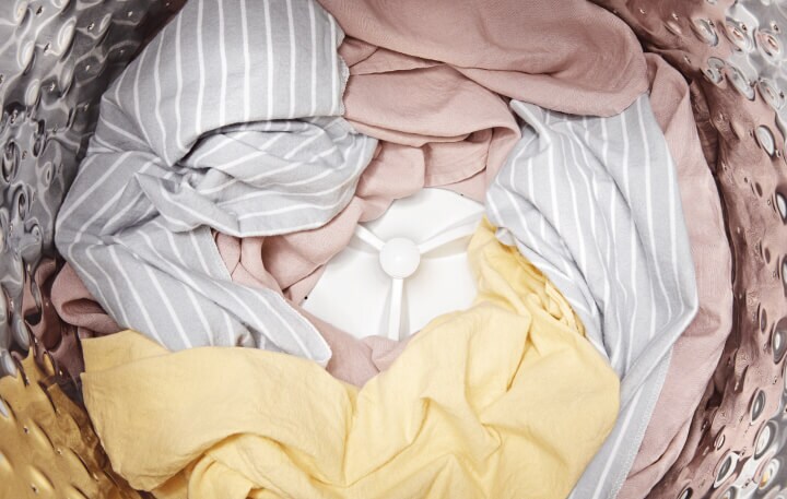 Close-up of dry, pastel clothing in top-load washer. Close-up of dry, pastel clothing in top-load washer.