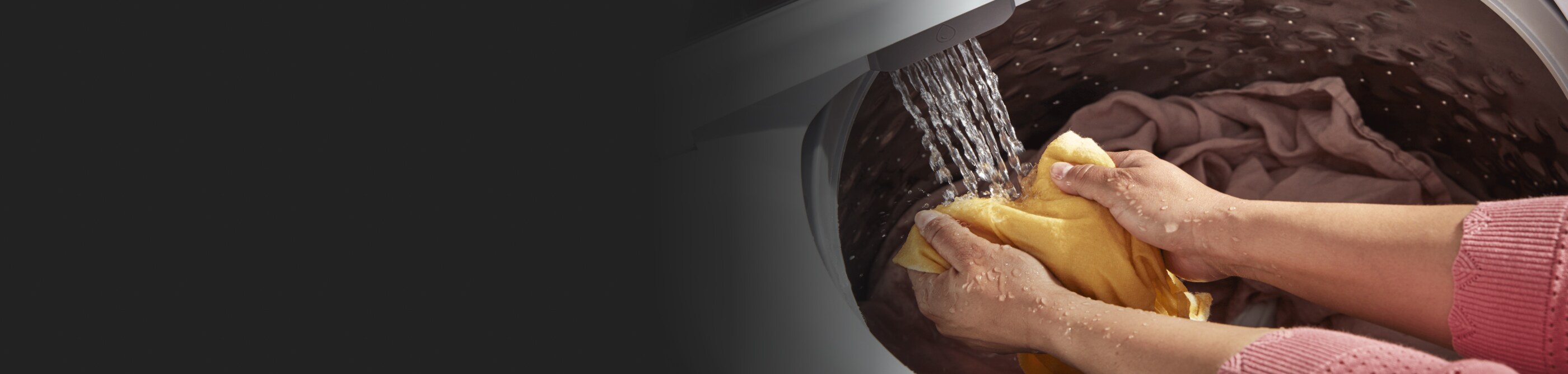 Person pretreating yellow clothing in washer water stream.