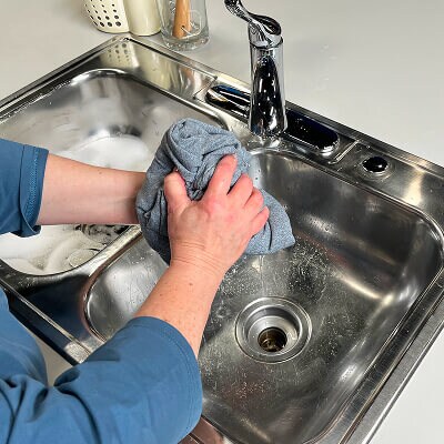 A person squeezing water out of leggings over a sink