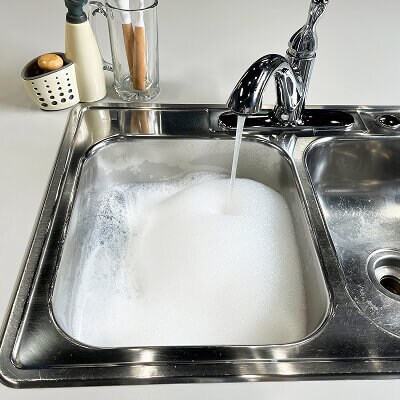 A sink filling with water and bubbles