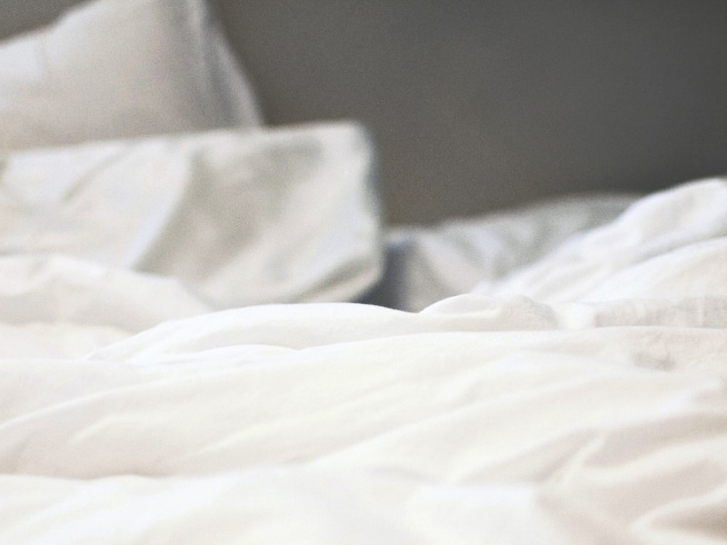 A cozy bed with white bed sheets