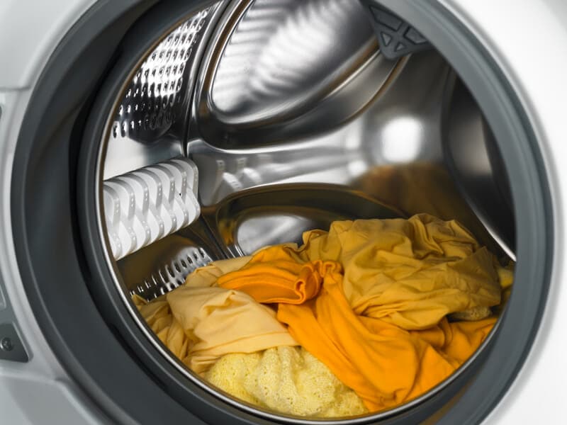 Yellow and orange laundry in a dryer. Yellow and orange laundry in a dryer.