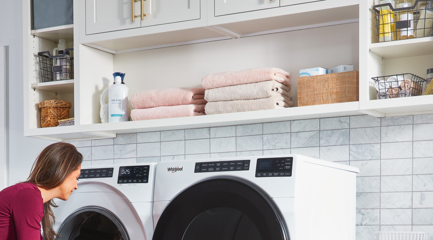 A woman washing towels with a Whirlpool® washer and dryer set A woman washing towels with a Whirlpool® washer and dryer set