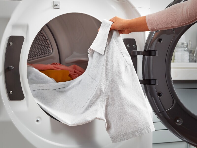 Person pulling a shirt out of a dryer Person pulling a shirt out of a dryer