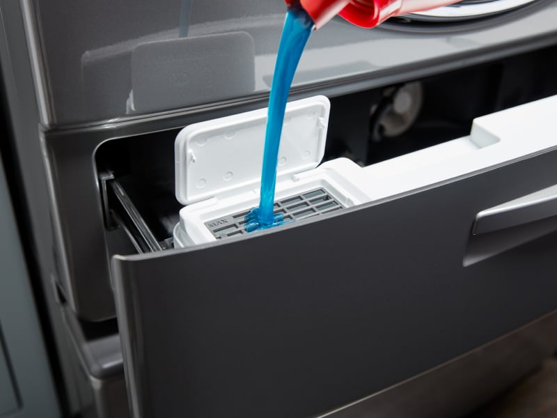 Detergent being loaded into a washer dispenser Detergent being loaded into a washer dispenser