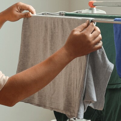A person hanging clothes on a drying rack