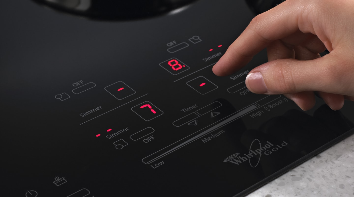 Person adjusting settings on an induction cooktop Person adjusting settings on an induction cooktop