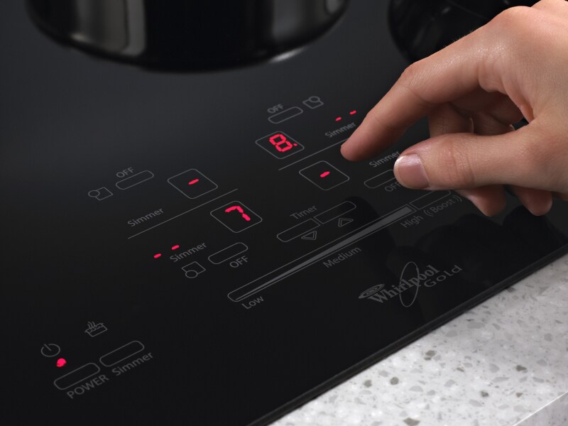 Person adjusting settings on an induction cooktop Person adjusting settings on an induction cooktop