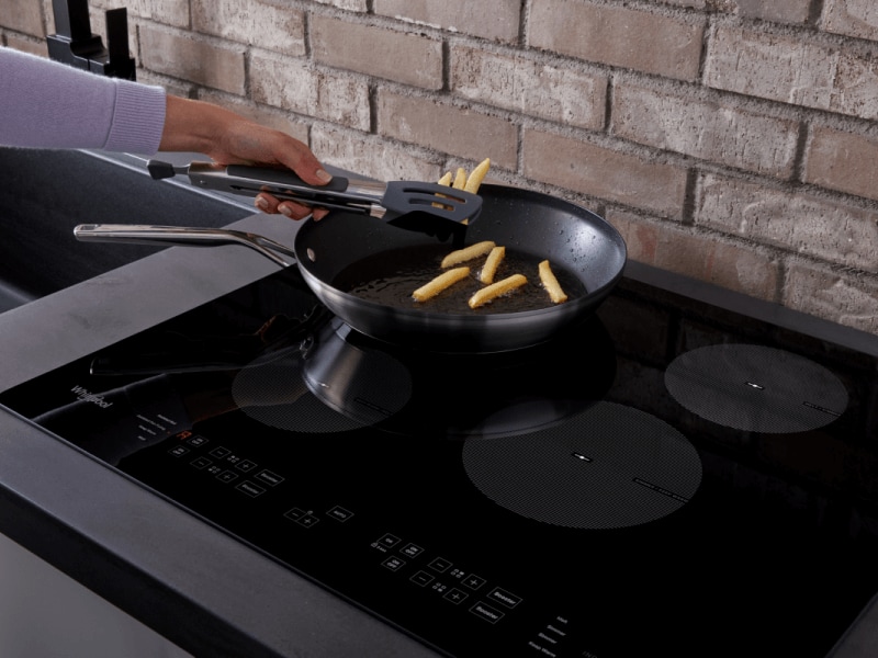 Person frying french fries in frying pan on stovetop Person frying french fries in frying pan on stovetop