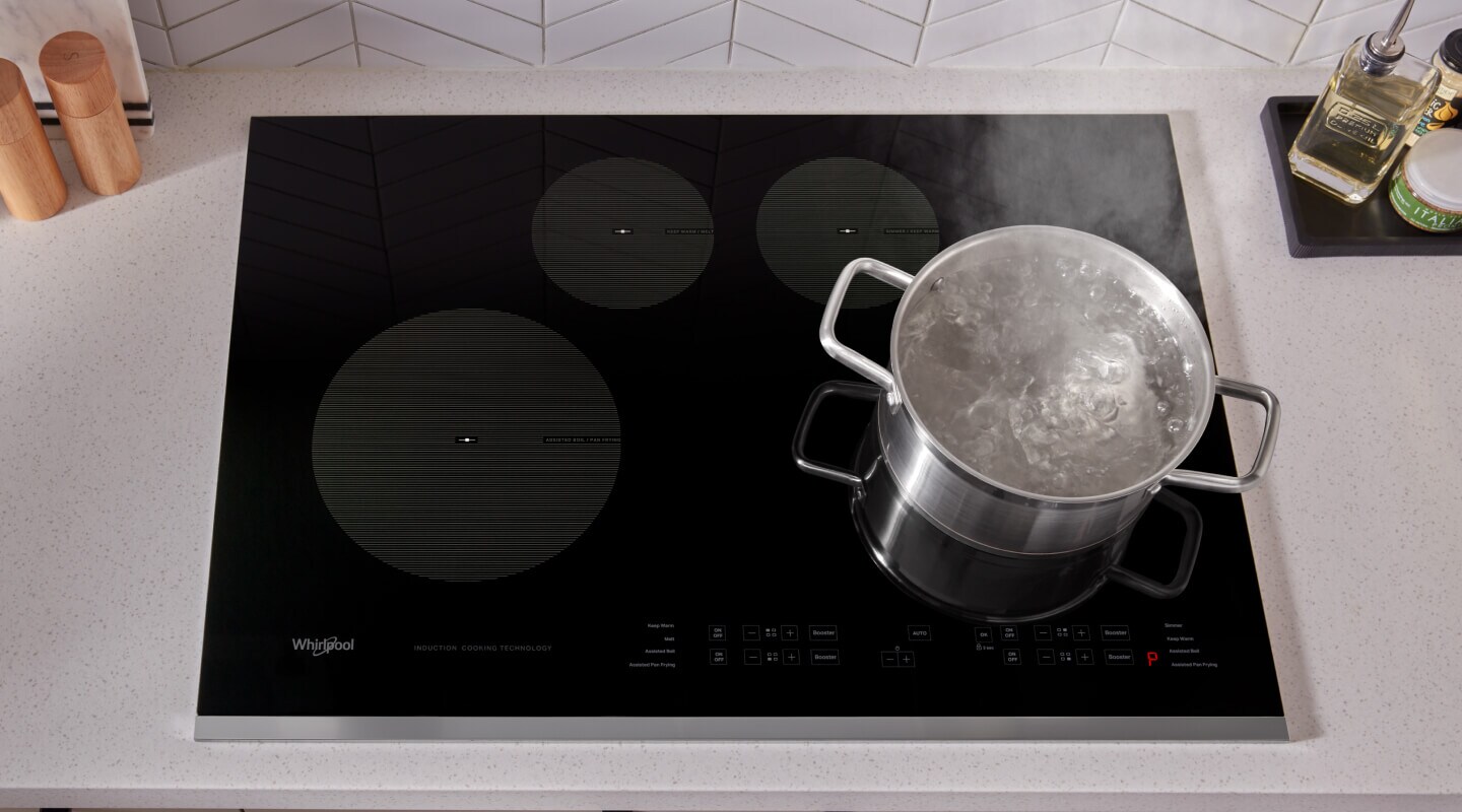 Water boiling in a stainless steel pot on top of a Whirlpool® Induction Cooktop