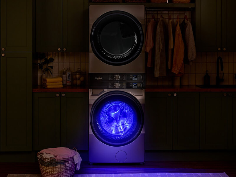 Blue light glowing from UV Clean Technology setting in a Whirlpool® Washer placed in a dark laundry room