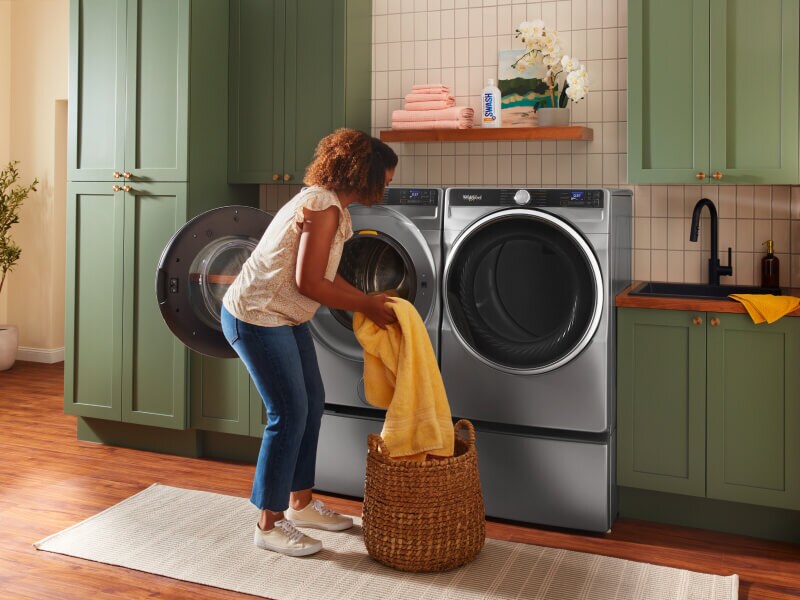 Person loading laundry into a Whirlpool® Front Load Washer