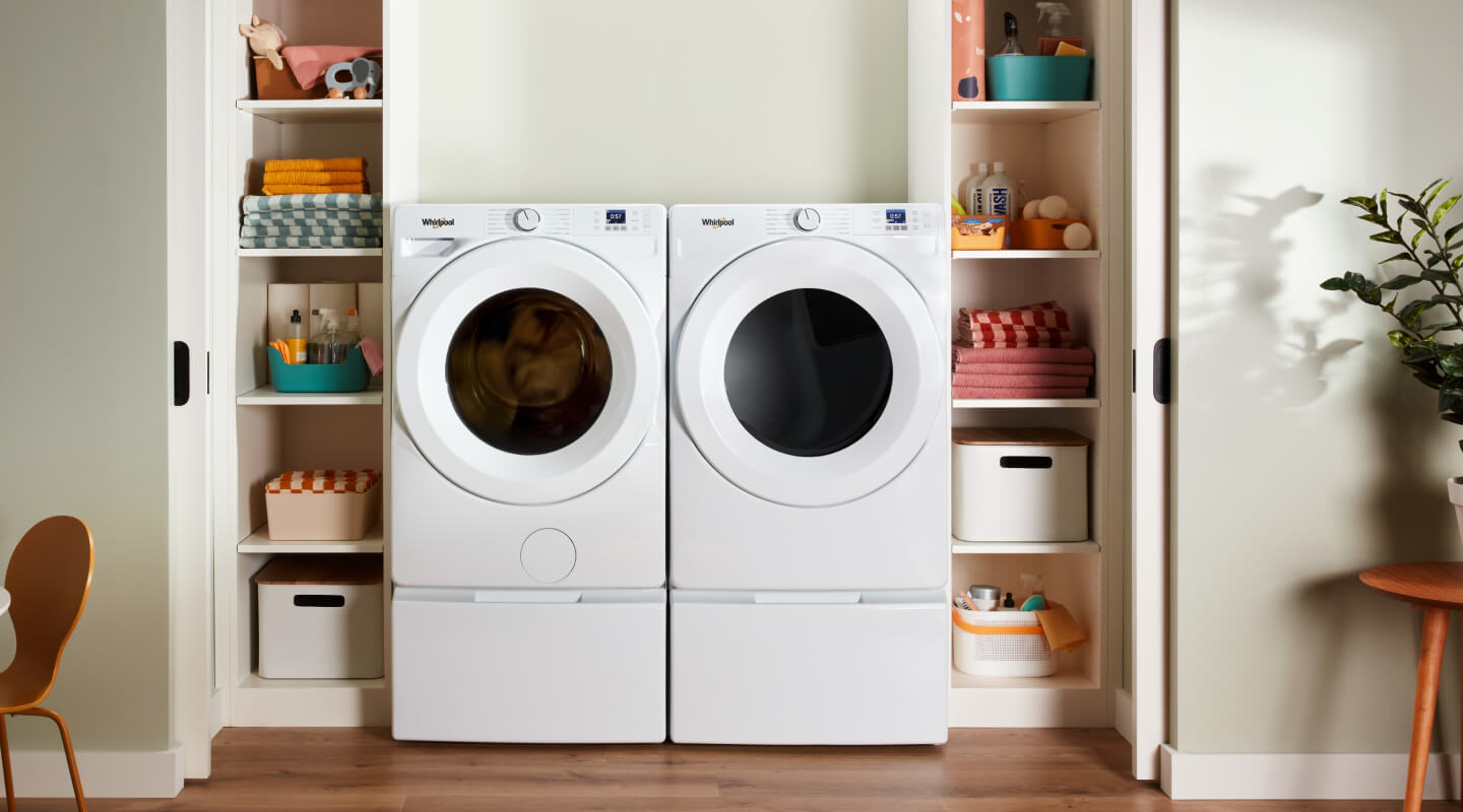 White Whirlpool® Front Load Washer and Dryer on pedestals between shelves