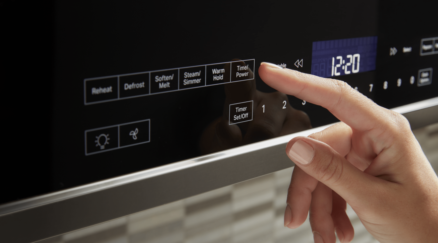 A person selects a microwave setting from a control panel A person selects a microwave setting from a control panel