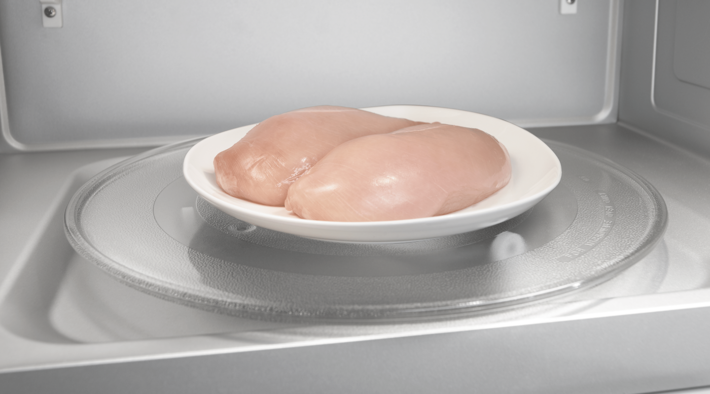 Two chicken breasts on a plate in a microwave Two chicken breasts on a plate in a microwave