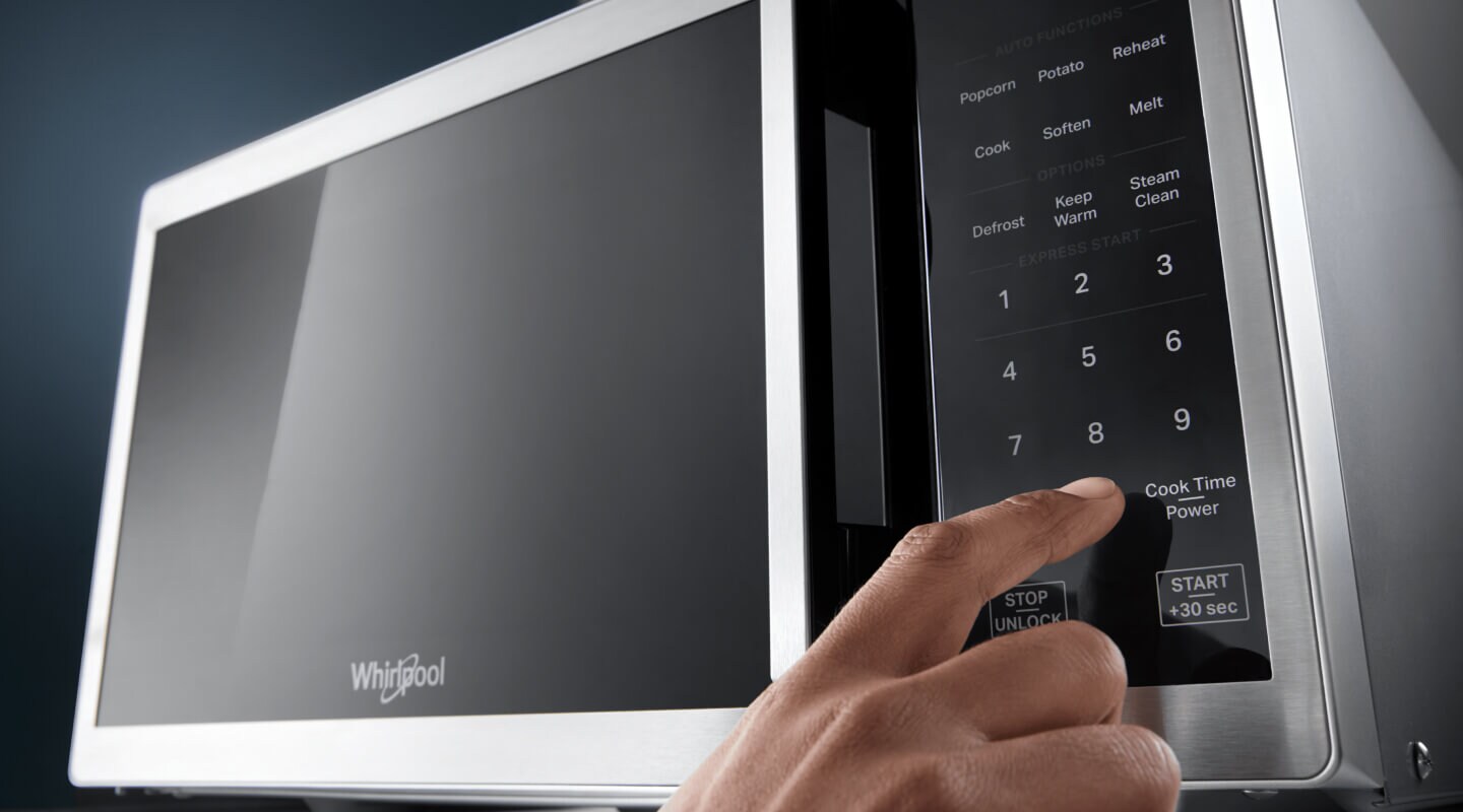 Person selecting a setting on a countertop microwave control panel Person selecting a setting on a countertop microwave control panel