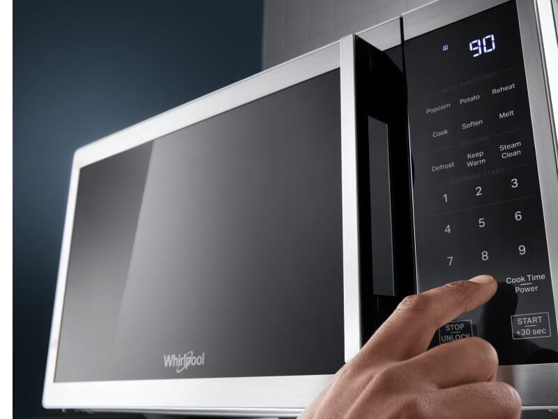 Person selecting a setting on a countertop microwave control panel Person selecting a setting on a countertop microwave control panel