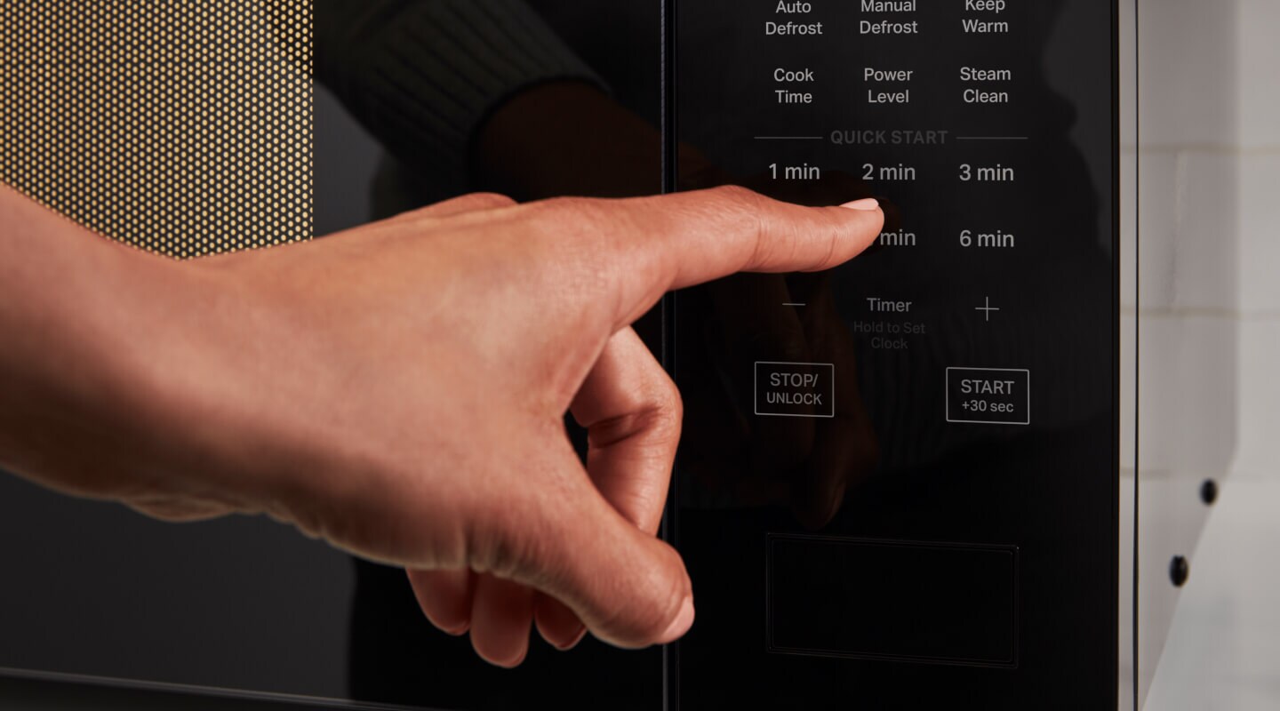 Person selecting a setting on a microwave control panel Person selecting a setting on a microwave control panel
