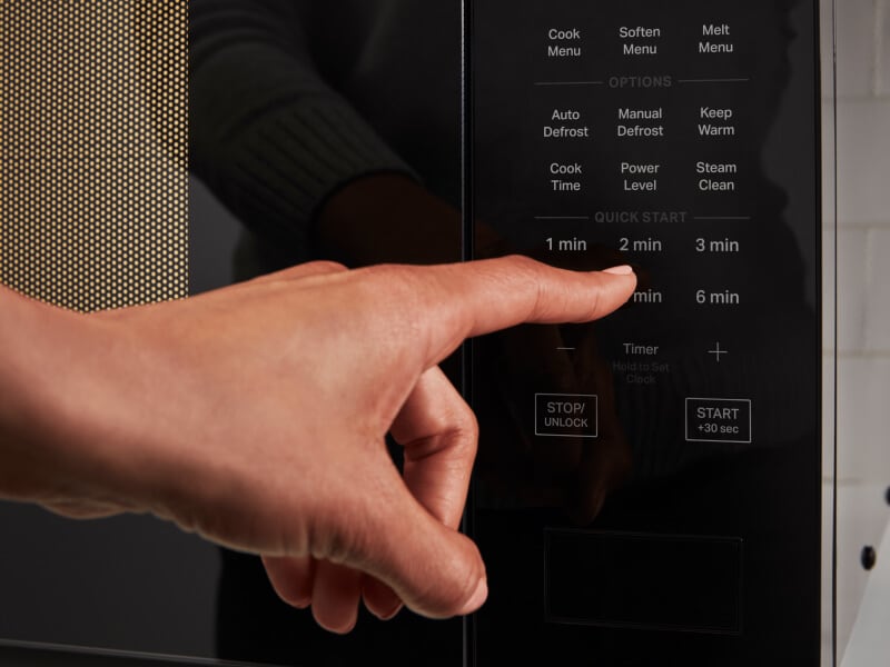 Person selecting a setting on a microwave control panel Person selecting a setting on a microwave control panel