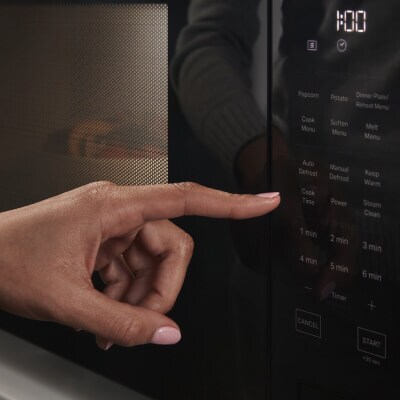 Person selecting settings on a microwave touchpad