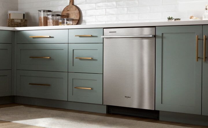 Stainless steel dishwasher in green kitchen 