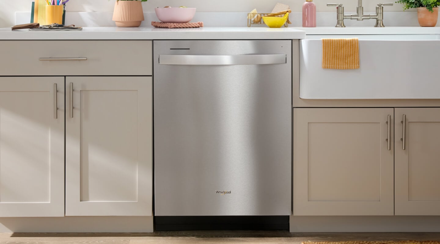 A top control dishwasher installed next to a farmhouse sink in a modern, neutral kitche