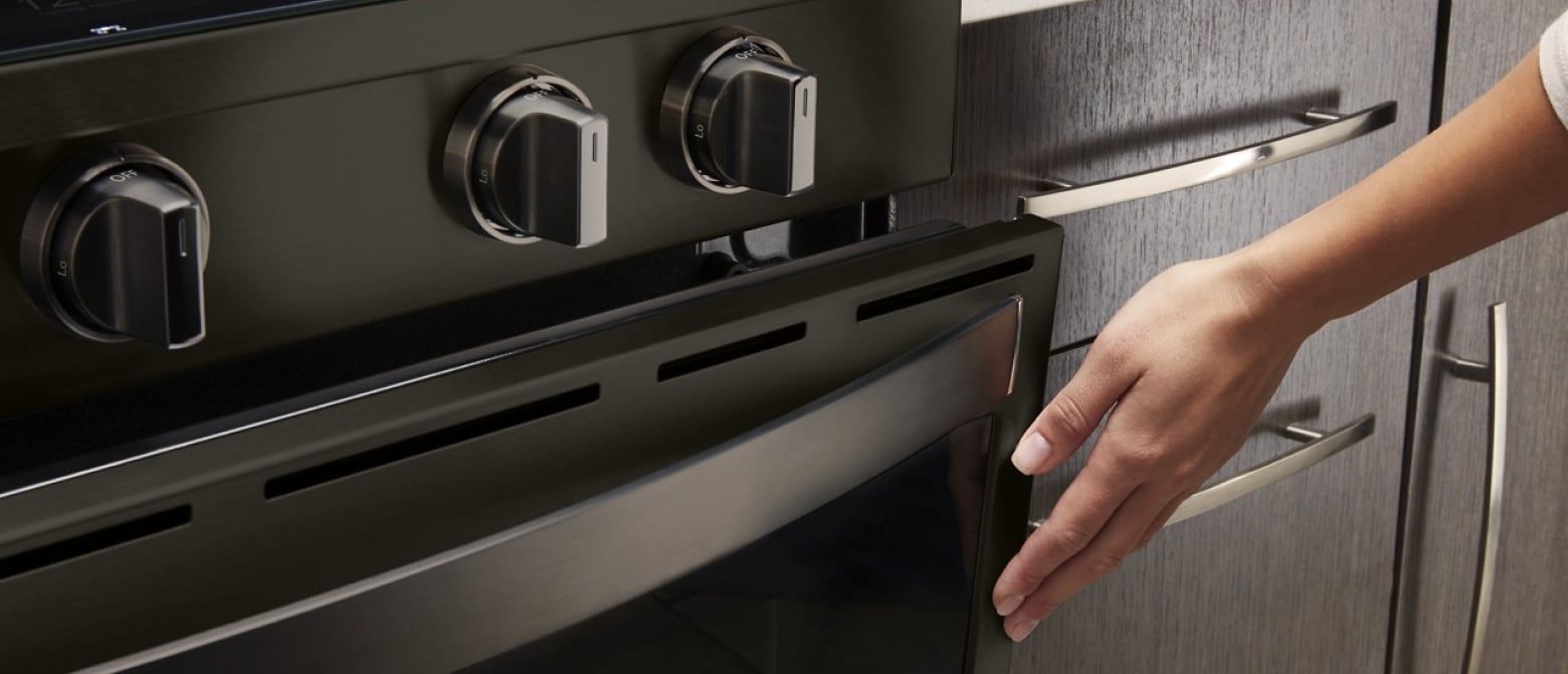 A hand closing an oven door. A hand closing an oven door.