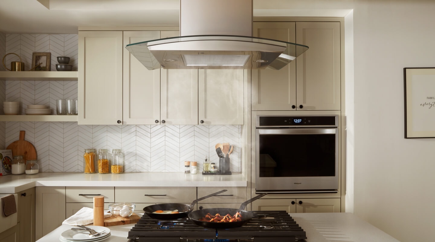 Bacon and eggs simmering on a gas cooktop underneath an island canopy hood Bacon and eggs simmering on a gas cooktop underneath an island canopy hood