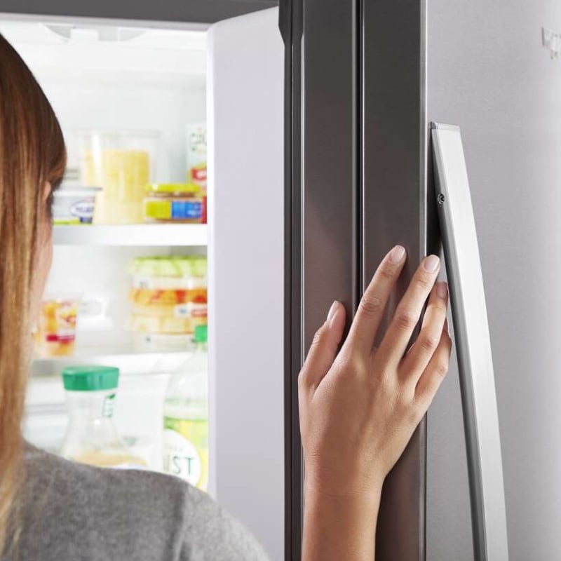 Close-up of a person’s hand on a fingerprint-resistant refrigerator door
