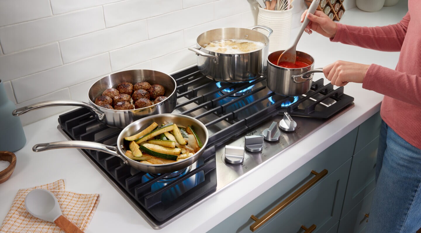A gas cooktop with food cooking on all four burners