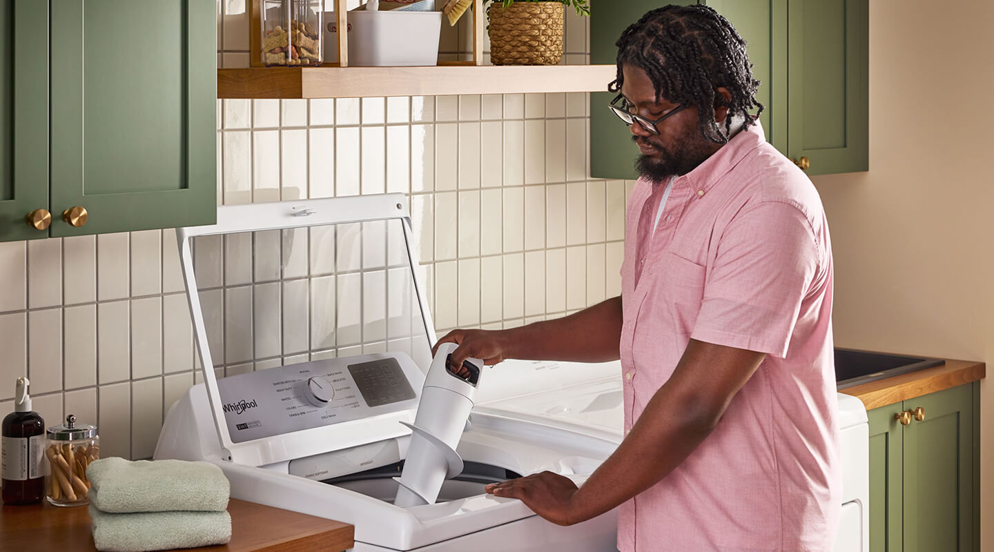 A person holding the agitator of an open washing machine