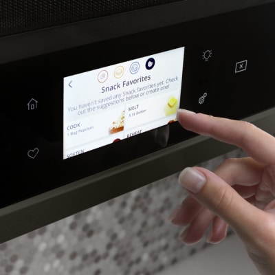 Person selecting settings on a Whirlpool® Smart Over-the-Range Microwave