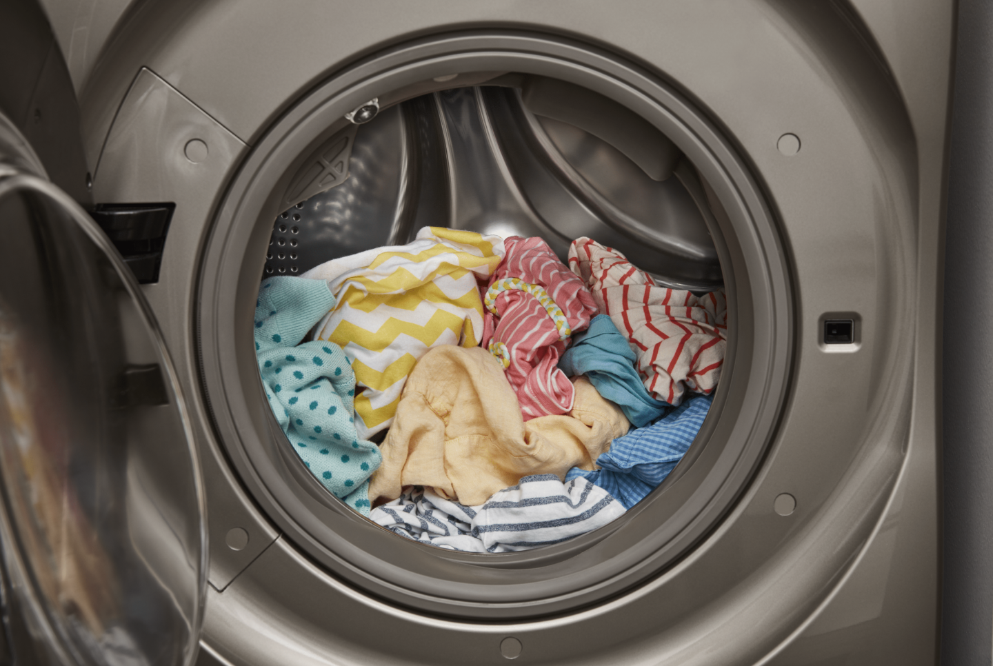 An open front load washer with a load of laundry inside An open front load washer with a load of laundry inside