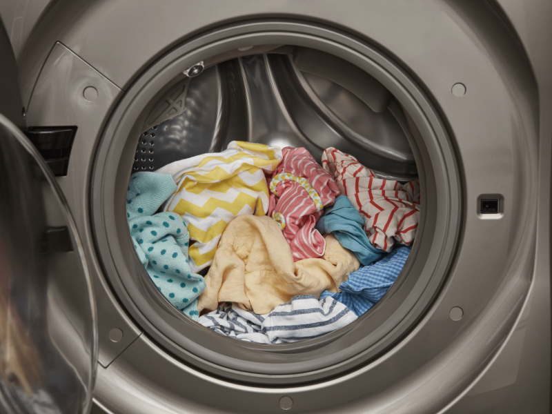 An open front load washer with a load of laundry inside An open front load washer with a load of laundry inside
