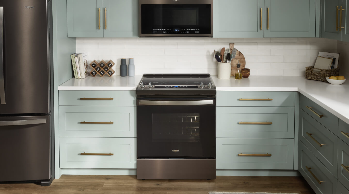 A kitchen with white counters, light cabinets and a Whirlpool® Range
