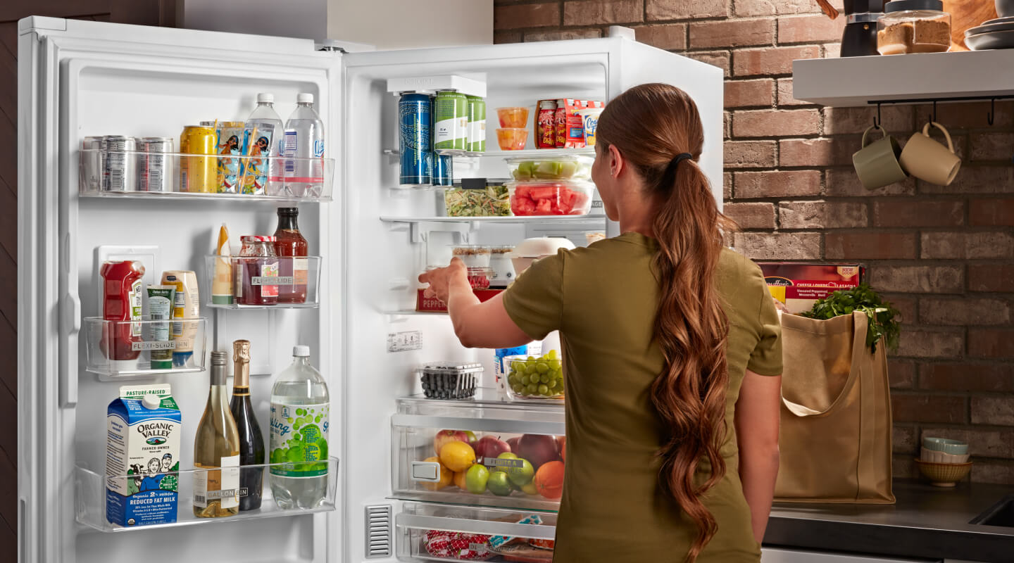 A person standing in front of their open fridge A person standing in front of their open fridge