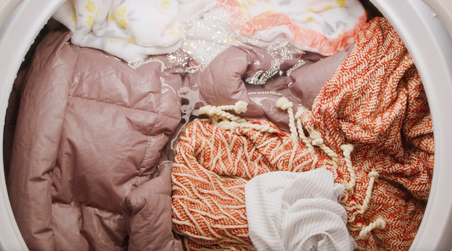A comforter and blankets soaking in a washing machine drum A comforter and blankets soaking in a washing machine drum