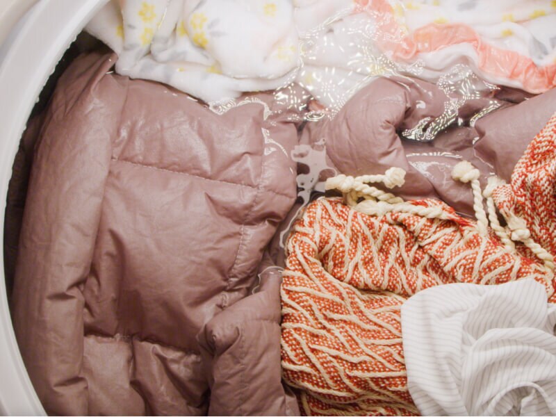 A comforter and blankets soaking in a washing machine drum A comforter and blankets soaking in a washing machine drum