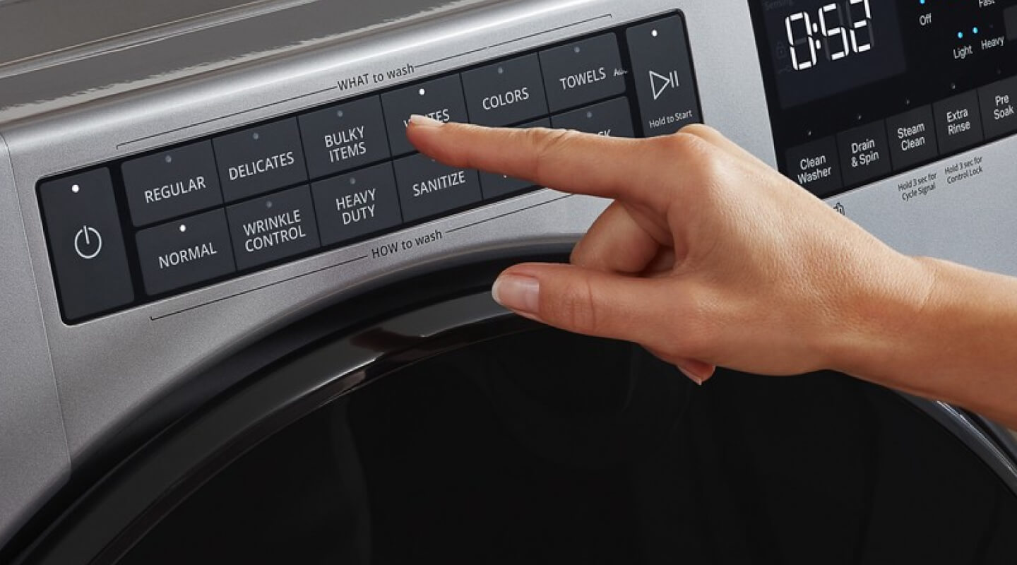 Hand selecting settings on a washing machine control panel Hand selecting settings on a washing machine control panel