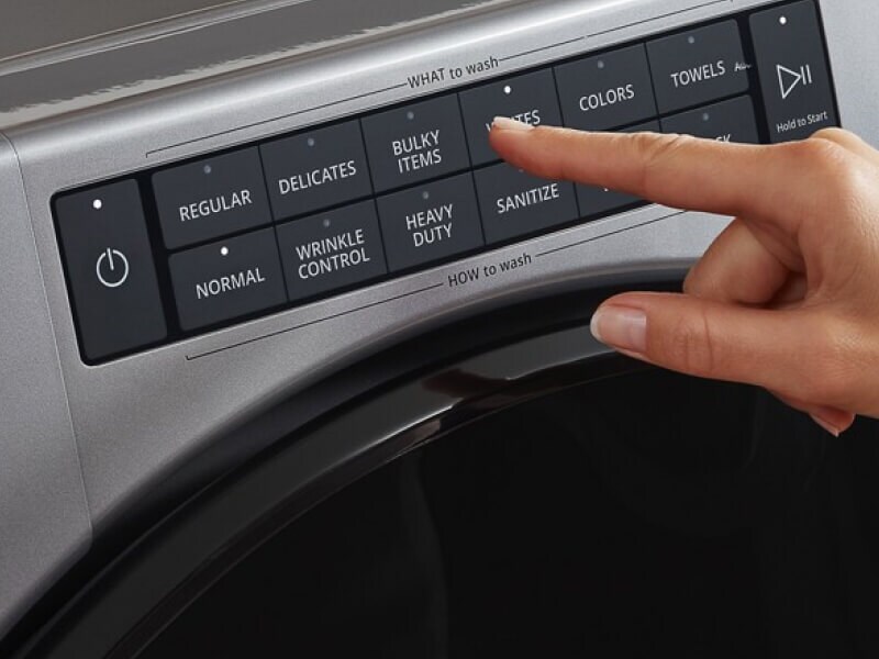 Hand selecting settings on a washing machine control panel Hand selecting settings on a washing machine control panel