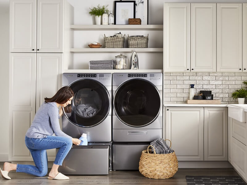 Person putting fabric softener into a washer pedestal Person putting fabric softener into a washer pedestal