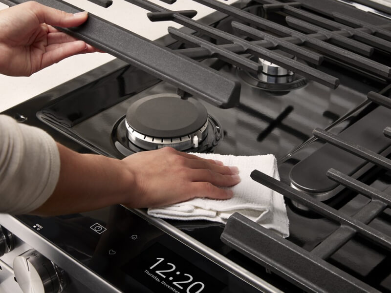 Hand wiping underneath oven grates Hand wiping underneath oven grates