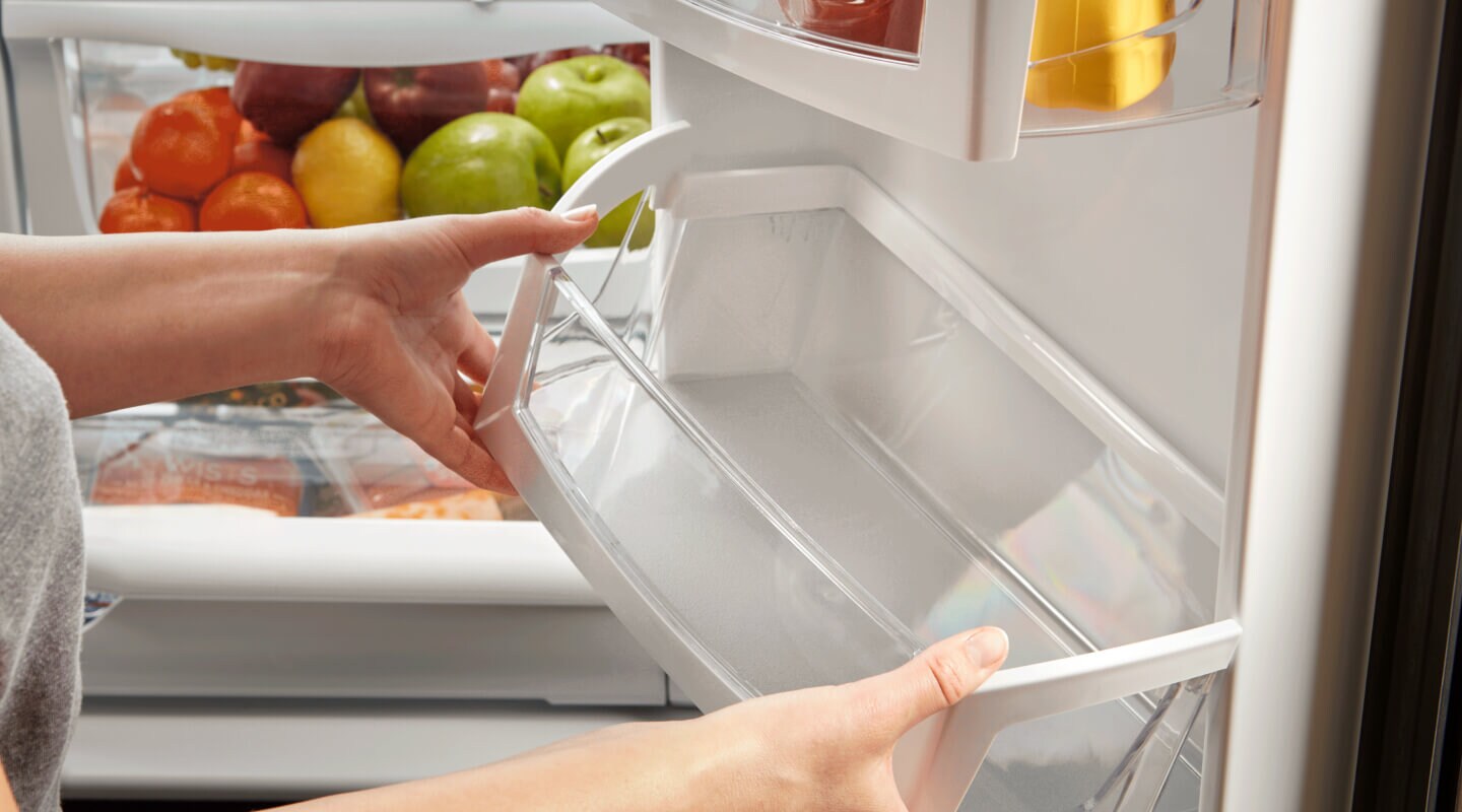 Person adding a clean bin to the inside of a refrigerator Person adding a clean bin to the inside of a refrigerator