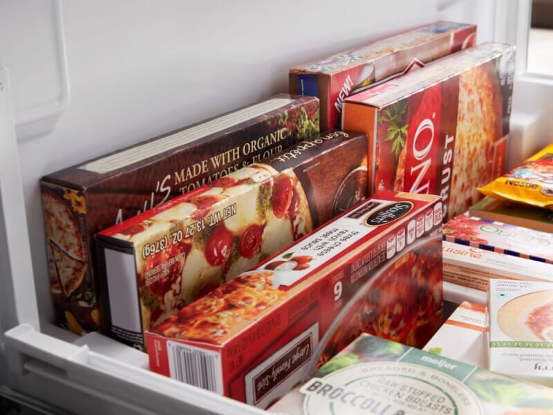 Frozen pizza, microwaveable meals and cookie dough inside a freezer bin Frozen pizza, microwaveable meals and cookie dough inside a freezer bin