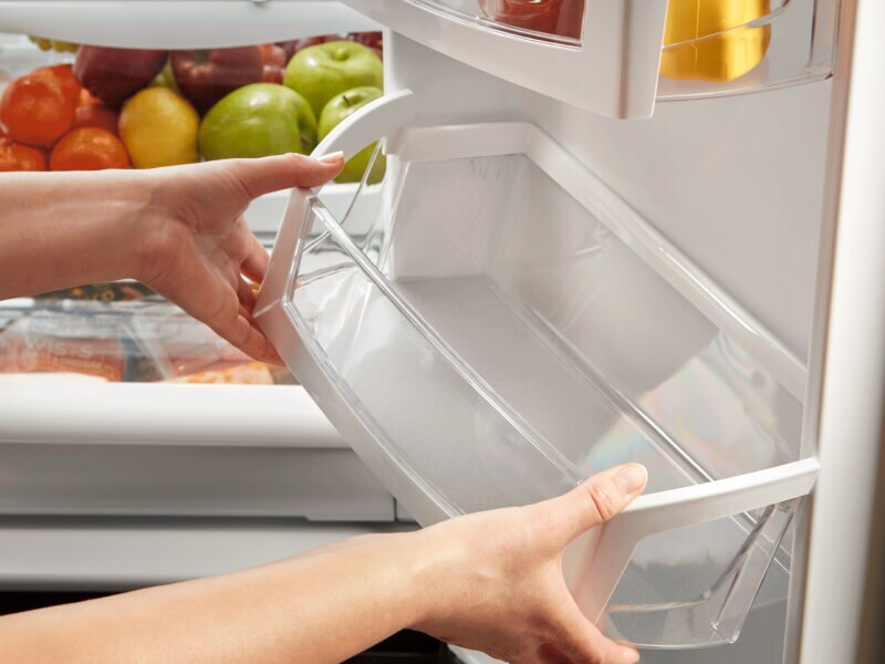 Person adding a clean bin to the inside of a refrigerator Person adding a clean bin to the inside of a refrigerator