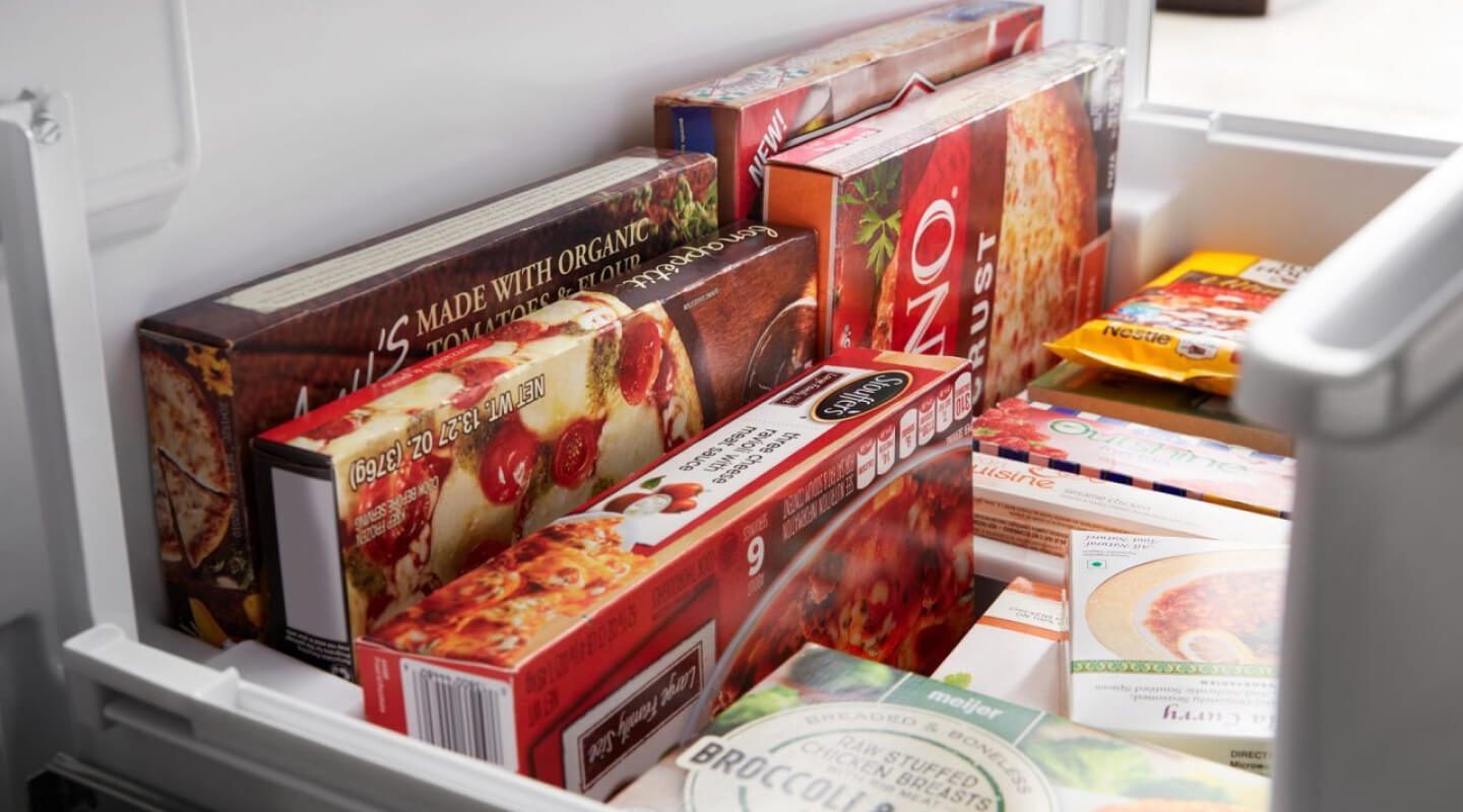 Frozen pizza, microwaveable meals and cookie dough inside a freezer bin Frozen pizza, microwaveable meals and cookie dough inside a freezer bin