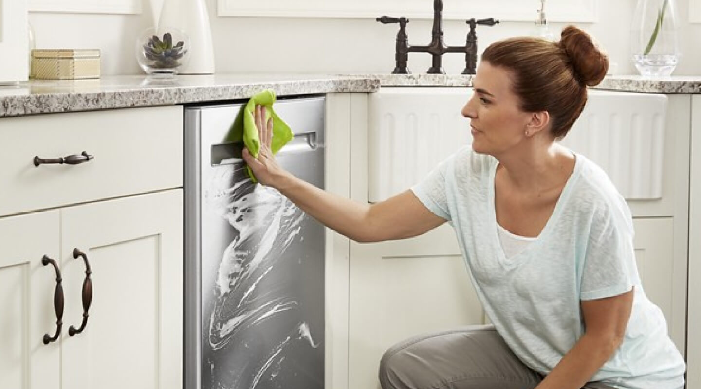 Person cleaning the exterior of a dishwasher Person cleaning the exterior of a dishwasher